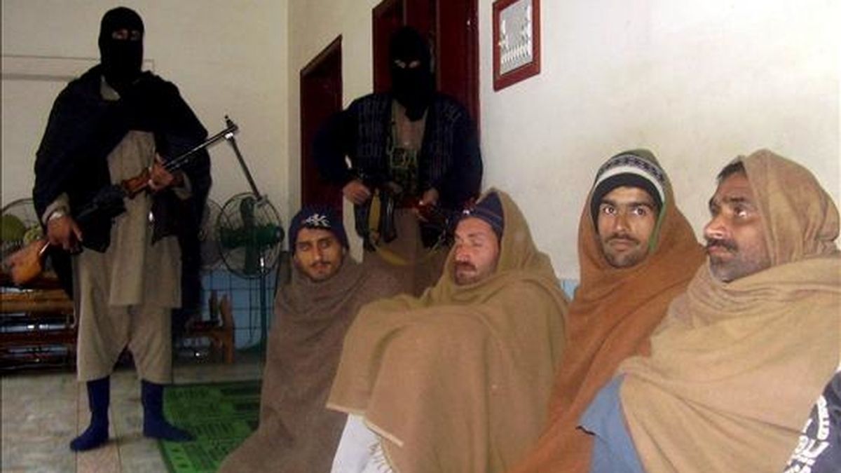 Dos talibanes vigilan a algunos de los policías paquistaníes secuestrados hoy y que posteriormente fueron liberados. EFE