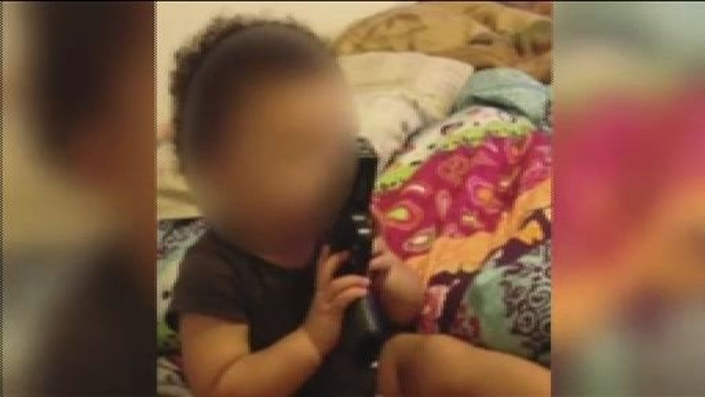 Un bebé se mete una pistola en la boca alentado por sus padres