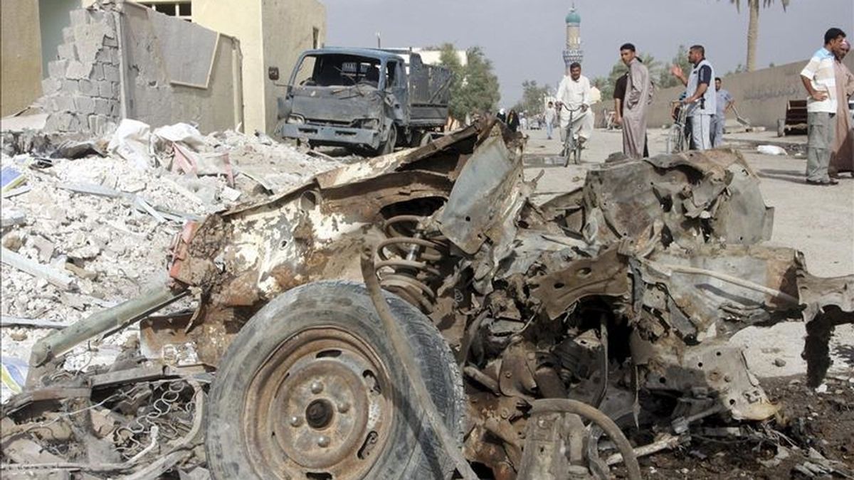 Iraquíes observan los restos de uno de los coches bomba que hicieron explosción en Faluya, Irak, ayer lunes, 11 de abril.Hoy otros dos nuevos ataques cerca de Bagdad han dejado 6 muertos. EFE