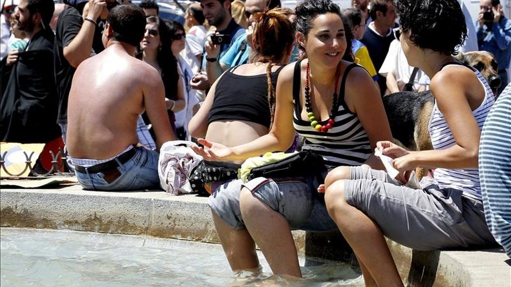 Dos jóvenes concentradas en la madrileña la Puerta del Sol se refrescan esta mañana en una fuente de la plaza. EFE Dos jóvenes concentradas en la madrileña la Puerta del Sol se refrescan esta mañana en una fuente de la plaza. EFE