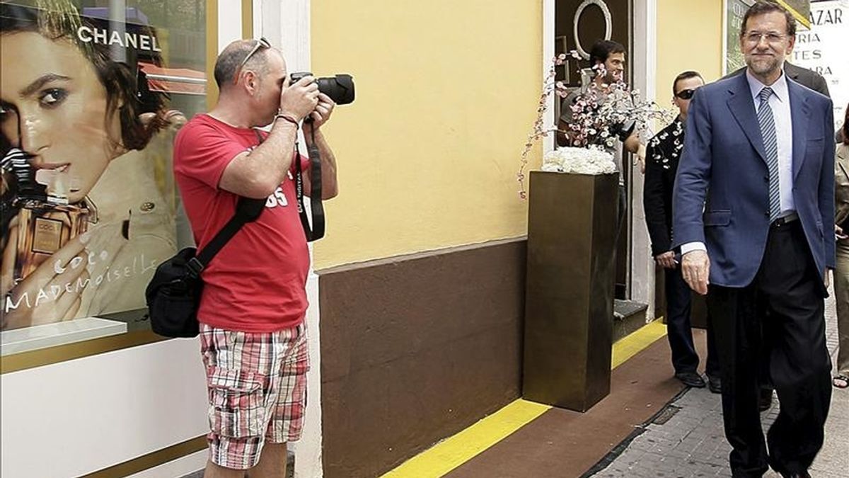 Un turista fotografía al presidente del Partido Popular (PP), Mariano Rajoy (d), durante un paseo por la capital tinerfeña tras intervir en un acto con empresarios y trabajadores autónomos de la isla. EFE