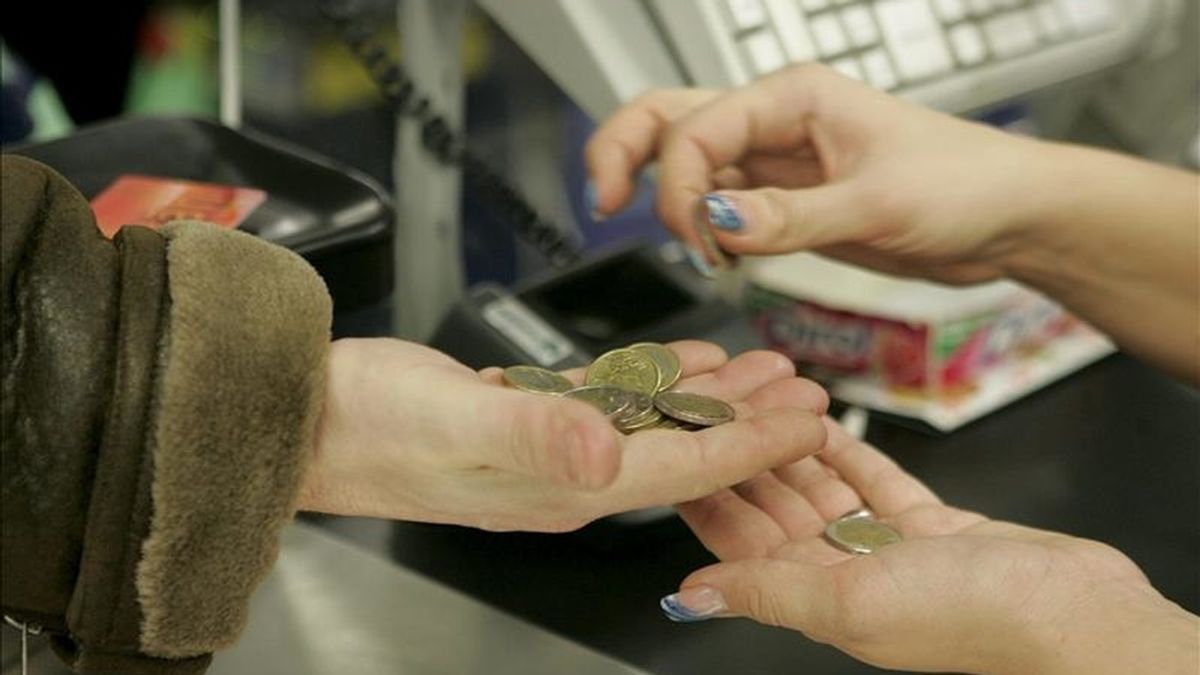 En la imagen, una cajera ayuda a un cliente a contar las monedas en un supermercado. EFE/Archivo