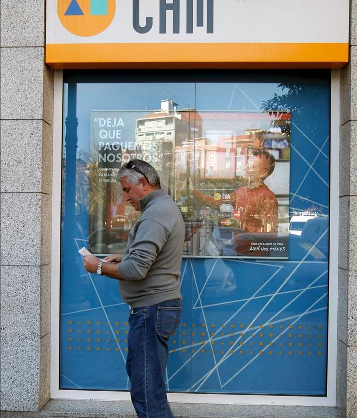 En la imagen, un usuario de la CAM consulta su libreta ante una de las oficinas de la caja de ahorros. EFE/Archivo