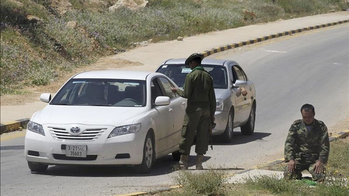 Un soldado libio de las fuerzas fieles al régimen del líder libio Muamar el-Gadafi inspecciona un coche mientras otro reza, en el punto de control de Gharyan, a unos 100 kilómetros al suroeste de Trípoli, Libia. EFE