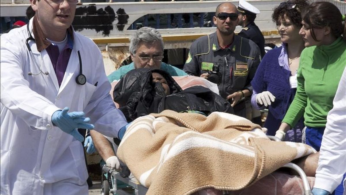 Médicos trasladan a una inmigrante en una camilla, tras llegar a la isla italiana de Lampedusa, procedente de Libia. EFE