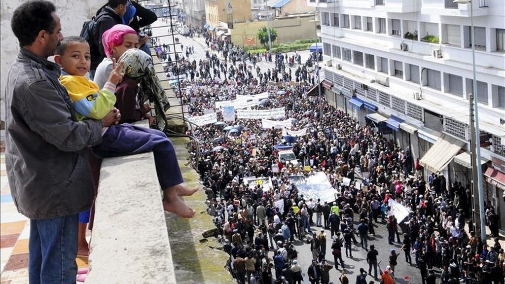 Varias personas observando el paso de una manifestación en petición de más democracia hoy en Casablanca (Marruecos). EFE