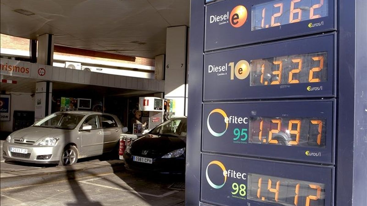Varios vehículos repostan en una gasolinera de la capital junto a un panel que informa de los precios de los carburantes. EFE/Archivo