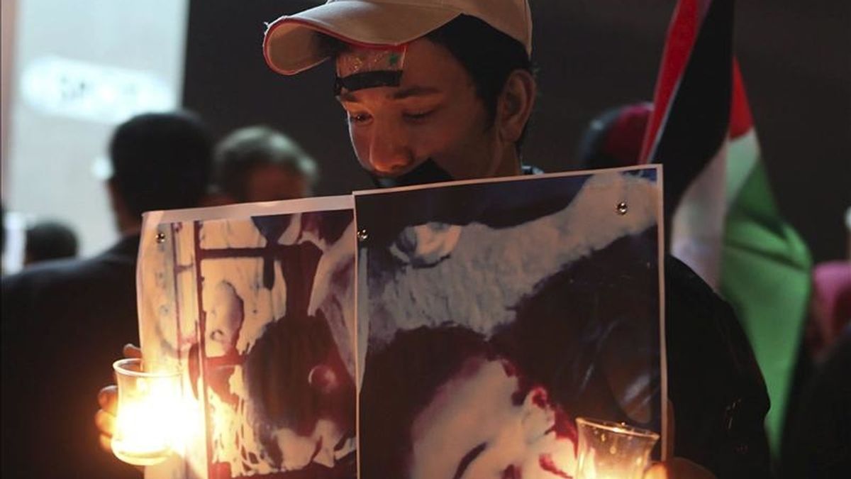 Un joven sirio residente en Jordania mostrando retratos de supuestas víctimas de la represión en Siria mientras participaba en una protesta convocada en los alrededores de la embajada de ese país en Amán este sábado. EFE