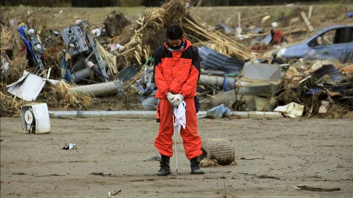Daisuke Sasaki (c), un bombero de 30 años, guarda un minuto de silencio mientras busca a personas desaparecidas, incluyendo tres de sus compañeros, en el primer día que tiene libre desde el terremoto y posterior tsunami que arrasó la costa nororiental japonesa el pasado 11 de marzo en la ciudad de Ishinomaki, en la prefectura de Miyagi (Japón). EFE