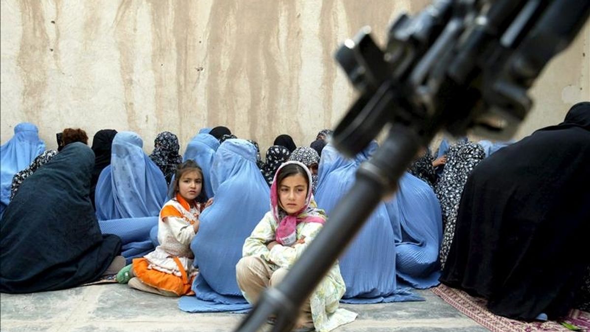 En la imagen, varias mujeres y niñas afganas esperan el 7 de abril de 2010 para recibir comida y atención médica cerca de un soldado italiano de la Fuerza de Asistencia Internacional de Seguridad de la OTAN (ISAF) que vigila la zona en el distrito de Shindand, en la provincia de Herat (Afganistán). EFE/Archivo