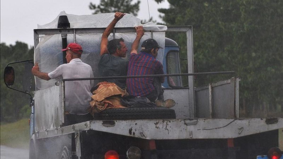 Tres hombres viajan en la parte trasera de un camión bajo una intensa lluvia provocada por la proximidad de un huracán en la ciudad de Pinar del Río, al oeste de La Habana (Cuba). EFE/Archivo