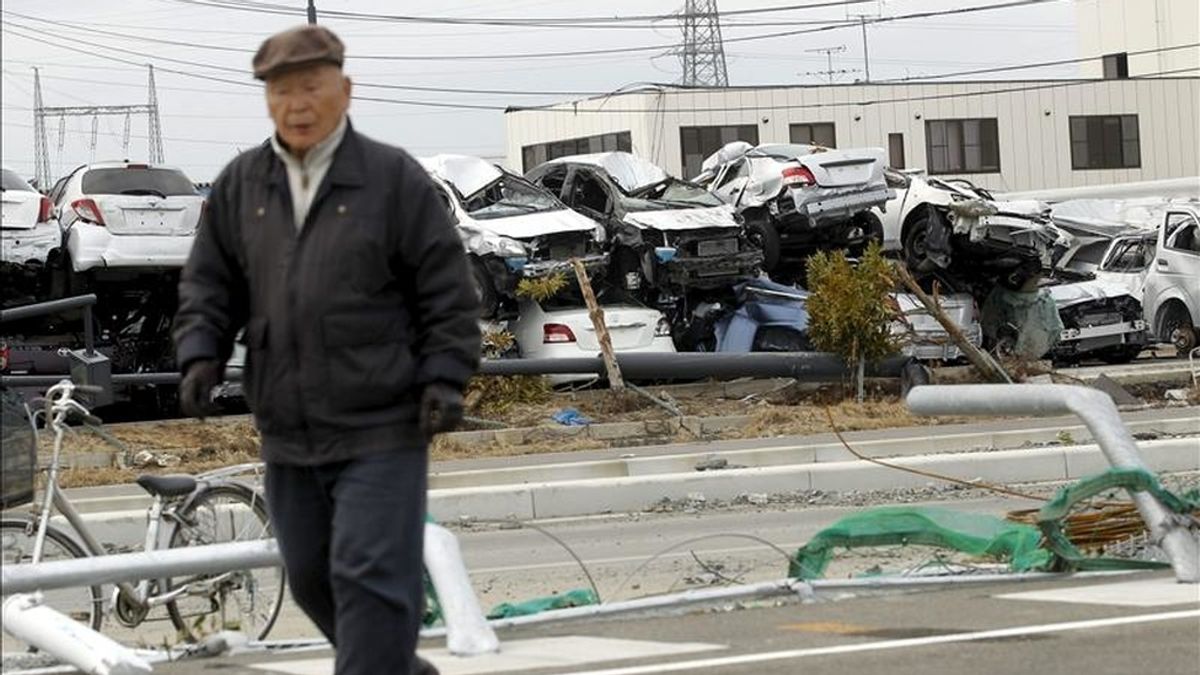 Un anciano camina cerca de varios vehículos Toyota destinados a su exportación, y que fueron destruidos por el tsunami, en el puerto de Sendai, prefectura de Miyagi, en el noreste de Japón. EFE/Archivo