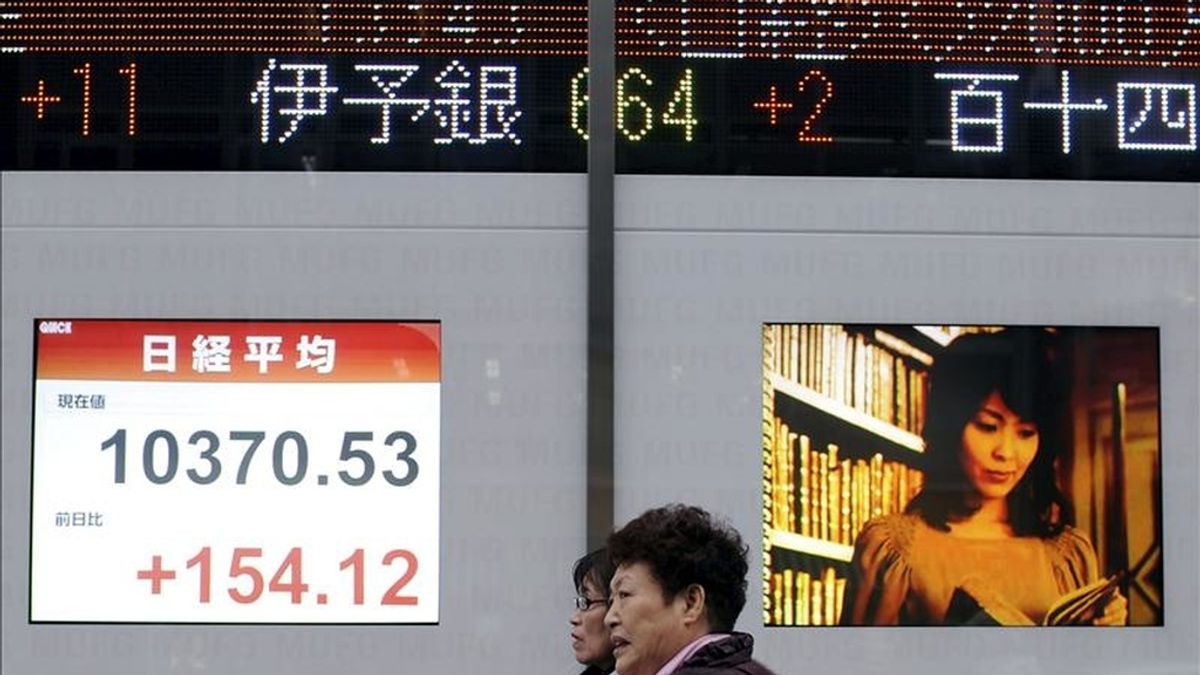 Dos mujeres caminan delante de una pantalla de la Bolsa de Tokio, Japón. EFE/Archivo