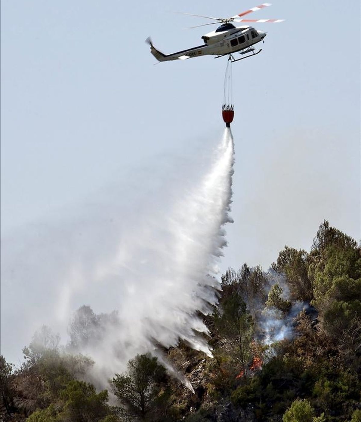 Un helicóptero arroja agua cerca de la población valenciana de Rótova tras el incendio declarado ayer en Benicolet, que anoche se dirigía hacia el paraje de Marxuquera y obligó al desalojo de varias viviendas. EFE