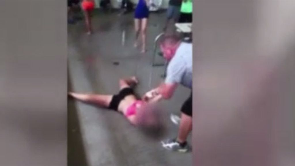 Un profesor arrastra a una alumna por el bordillo de la piscina