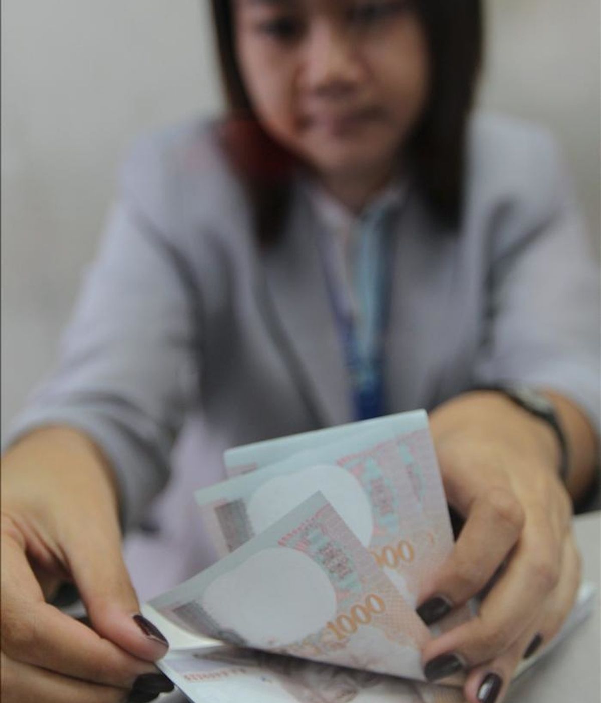 Una mujer cuenta dinero en un local de cambio de divisas en Bangkok, Tailandia. EFE/Archivo