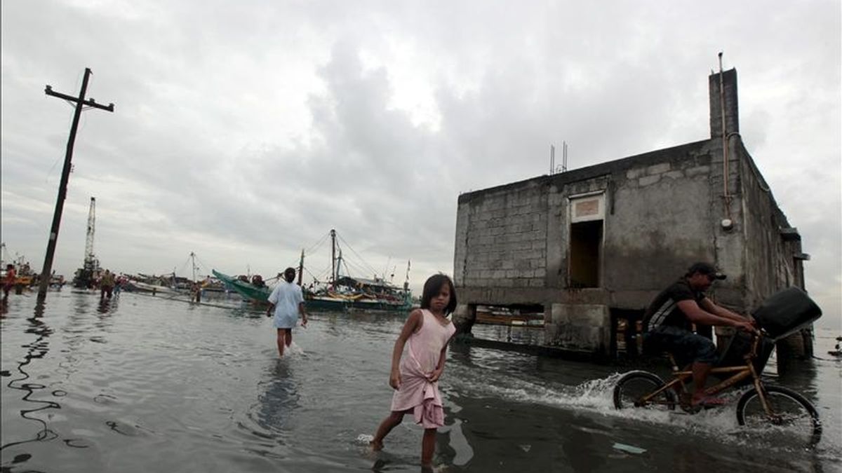 Los residentes caminan en una zona inundada de su localidad tras el paso de la tormenta tropical 'Aere' en Manila, Filipinas. EFE