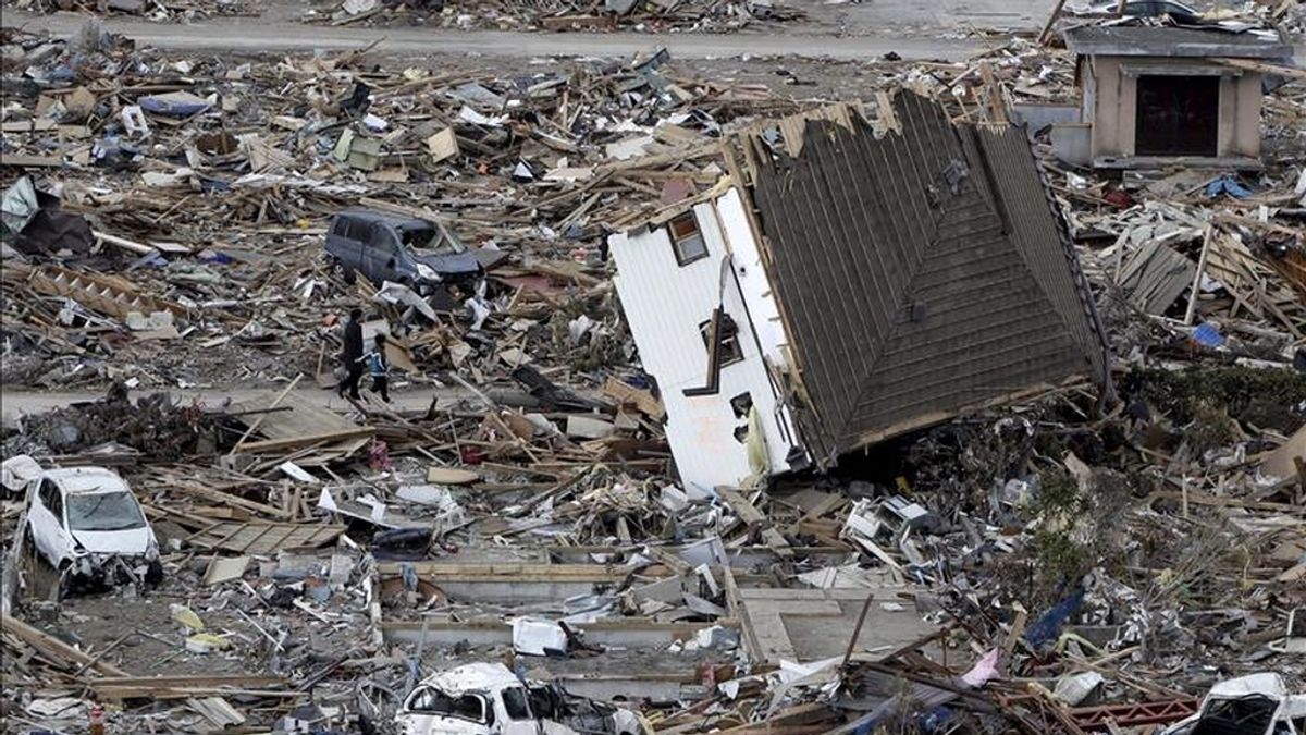 Un padre y su hijo parecen diminutos en comparación con la enormidad de los escombros que cubren por completo la devastada población costera de Ofunato, en la prefectura de Iwate, noreste de Japón. EFE
