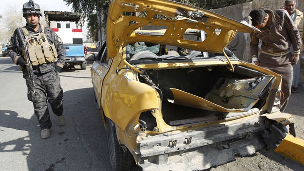 Un policía examina un coche tras un atentado con bombas en Bagdad Un policía examina un coche tras un atentado con bombas en Bagdad