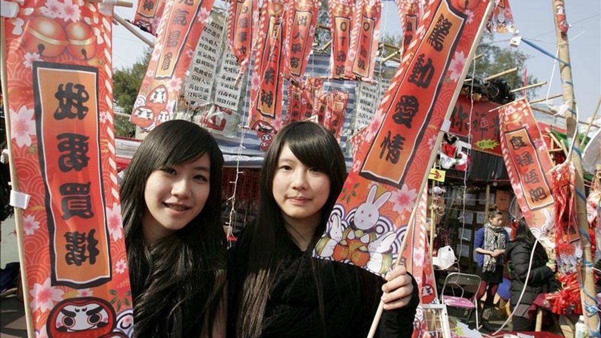 Dos chicas posan con unas tradicionales banderitas con buenos deseos para el año nuevo durante los preparativos para la llegada del Año del Conejo en el zodíaco chino, período que durará del 3 de febrero al 22 de enero de 2012, en un mercado de Victoria Park, en Hong Kong, China, hoy, lunes 31 de enero de 2011. EFE