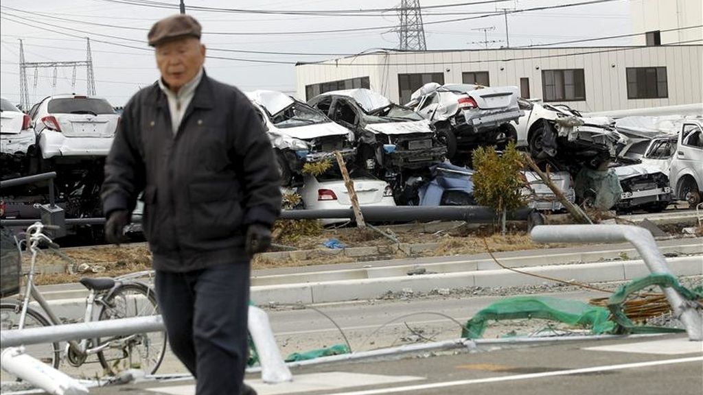 Un anciano camina cerca de varios vehículos Toyota destinados a su exportación, y que fueron destruidos por el tsunami. EFE/Archivo