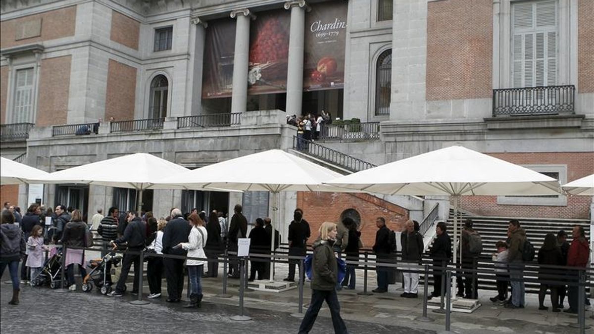 Grandes sombrillas protegen de la lluvia a una larga cola de personas que han elegido esta mañana de Jueves Santo para disfrutar de una visita al Museo del Prado. EFE