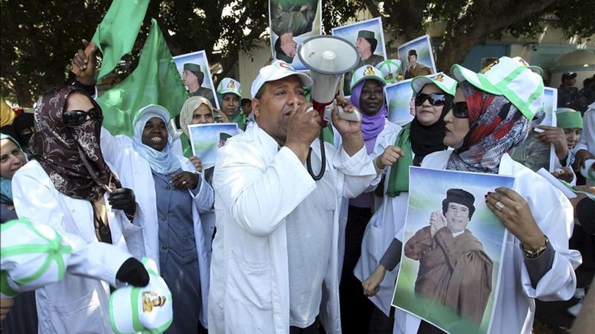 Libios leales al líder Muamar el Gadafi gritan consignas y sostienen imágenes de él durante una protesta en contra de los bombardeos aéreos de la coalición aliada sobre Libia, en las afueras de las oficinas de la ONU, en Trípoli, Libia. EFE