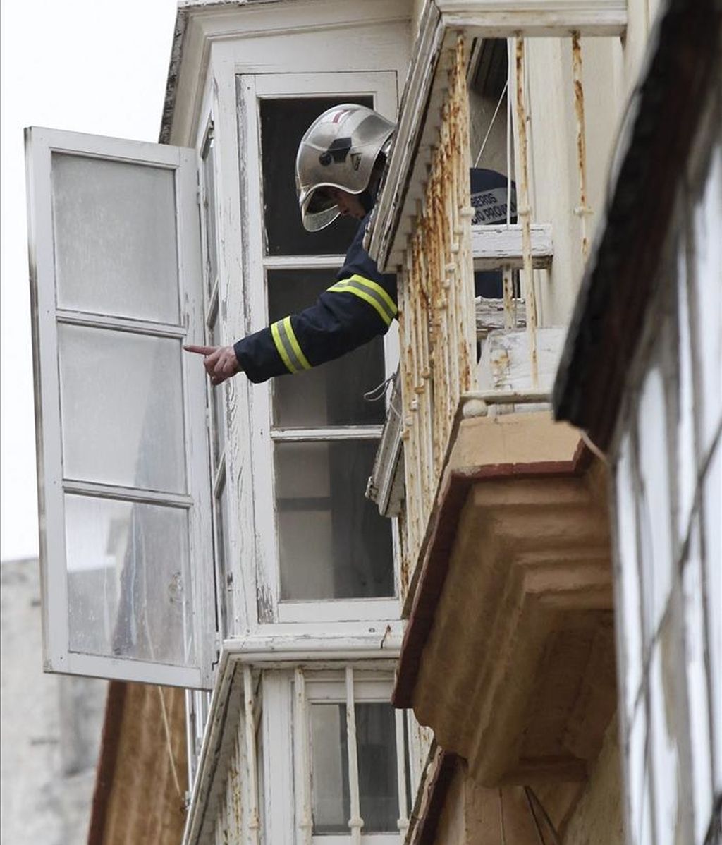 Un bombero asoma por la ventana de la vivienda en Cádiz, donde esta mañana ha fallecido un hombre minusvalido de 53 años al incendiarse el sillón automático en el que estaba sentado y que estaba conectado a la corriente eléctrica. EFE