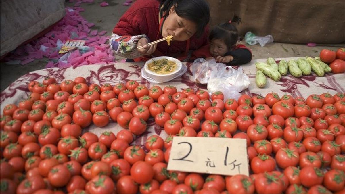 Una mujer come fideos chinos en su puesto de tomates en Qingdao (China). China registró su primer déficit comercial en seis años entre enero y marzo. EFE/Archivo