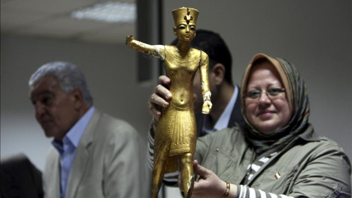 Una arqueóloga sin identificar (d) sostiene una estatua de madera dorada tras regresar al Museo Egipcio, mientras el ministro de Estado de Antigüedades, Zahi Hawas (i), conversa con los medios en El Cairo (Egipto). El arqueólogo egipcio Salah Mohamed encontró hoy por casualidad una maleta en el metro de El Cairo que contenía cuatro piezas del ajuar funerario de Tutankamón. EFE