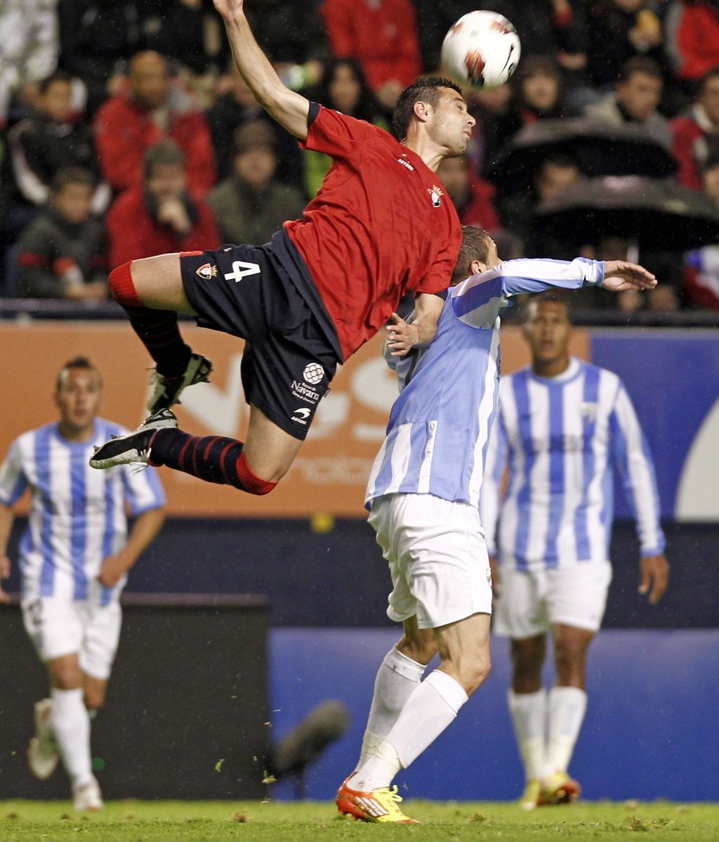 El defensa de Osasuna Miguel Flaño cabecea un balón ante el centrocampista del Málaga, Joaquín Sánchez El defensa de Osasuna Miguel Flaño cabecea un balón ante el centrocampista del Málaga, Joaquín Sánchez