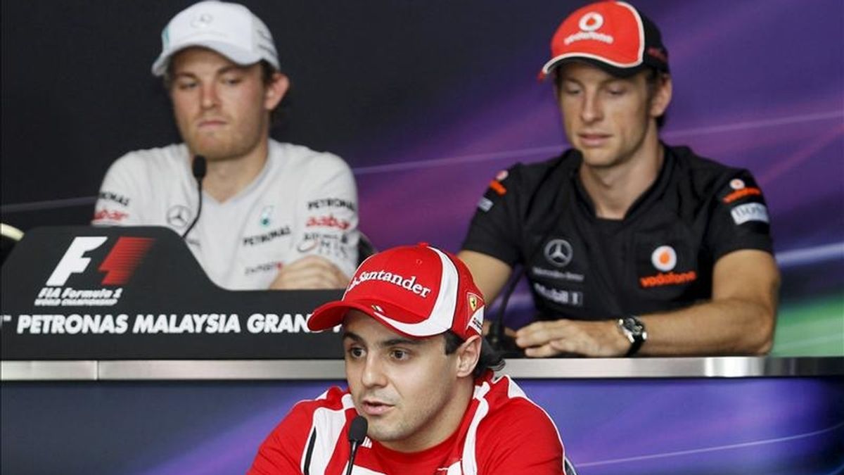 El piloto brasileño de Fórmula Uno de la escudería Ferrari, Felipe Massa (delante), el británico de McLaren Mercedes, Jenson Button (dcha), y el alemán de Mercedes GP, Nico Rosberg, atienden a los medios durante la rueda de prensa ofrecida en el circuito de Sepang. EFE