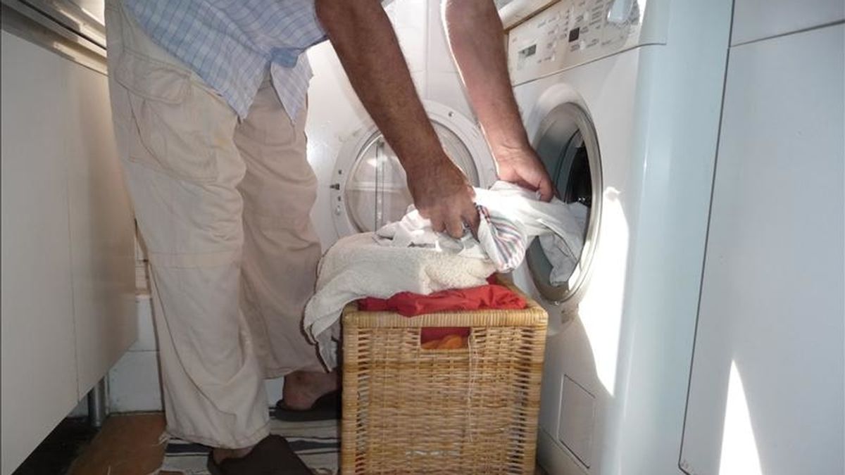 Un hombre introduce ropa en una lavadora doméstica. EFE/Archivo