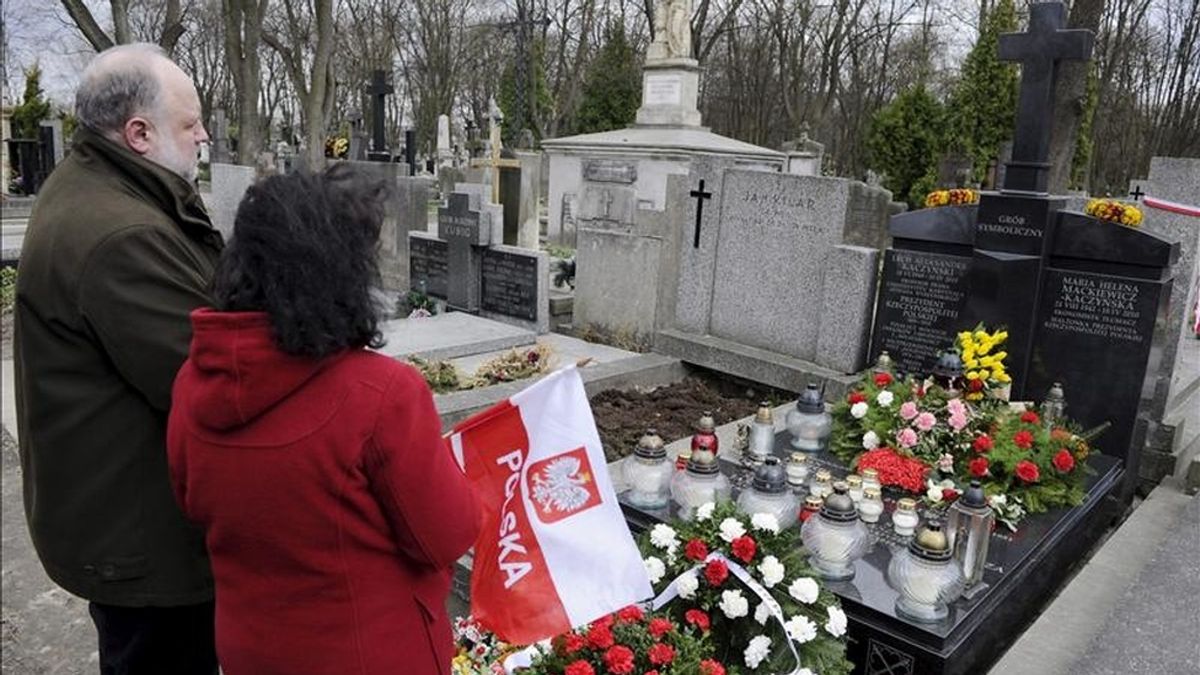 Ciudadanos rezando ante la tumba simbólica del presidente polaco Lech Kaczynski y su esposa María durante un homenaje a las víctimas del accidente del avión presidencial polaco en el cementerio militar Powazki, en Varsovia, hoy. EFE
