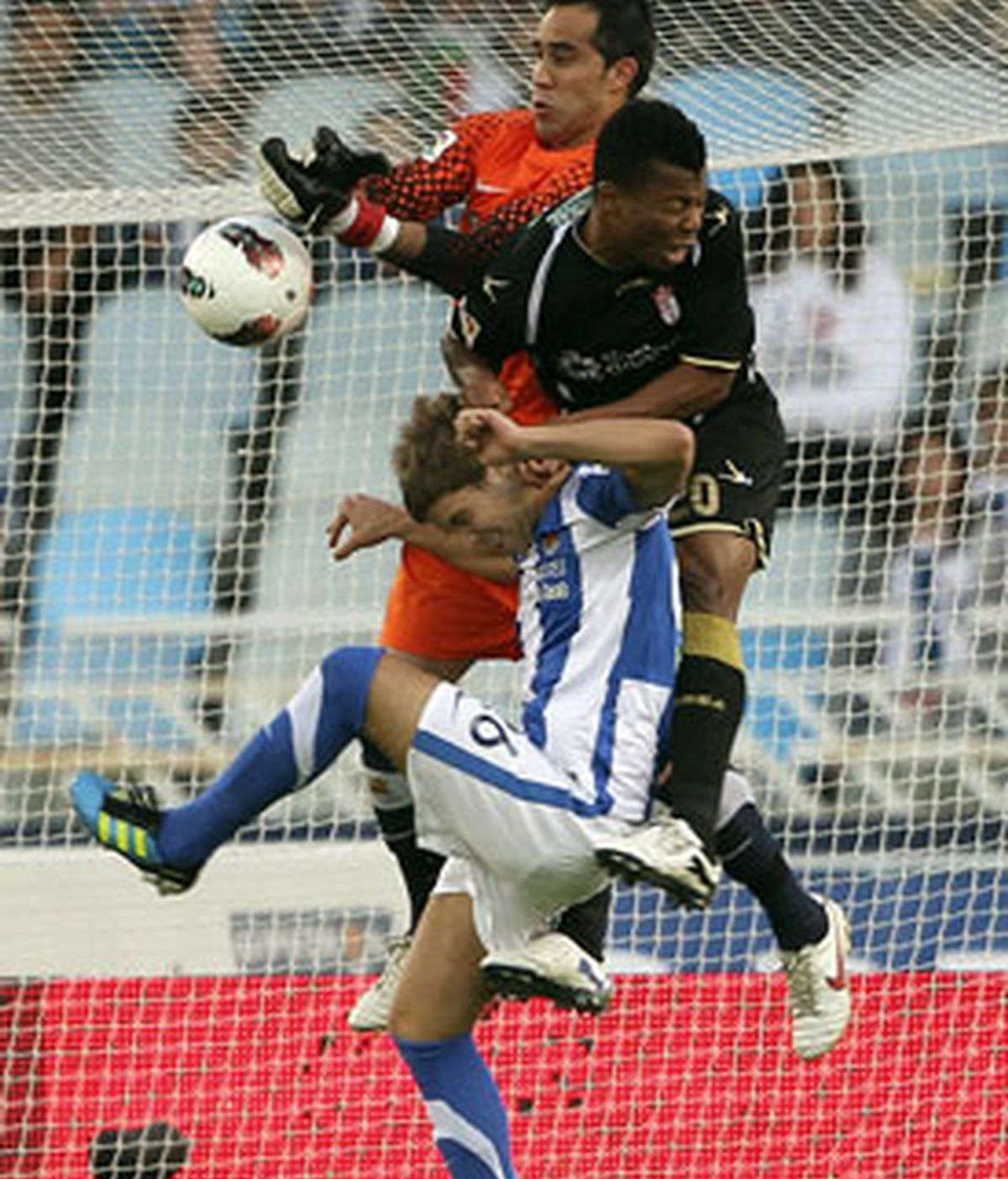 Ikechukwu Uche lucha por el balón con el defensa y el portero de la Real Sociedad, Íñigo Martínez y Caludio Bravo. Foto: EFE.