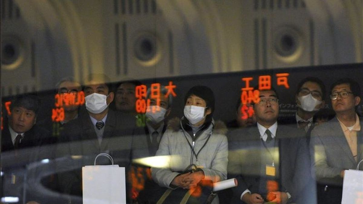 Los visitantes observan los indicadores electrónicos con las cifras de la Bolsa de Valores de Tokio. EFE/Archivo