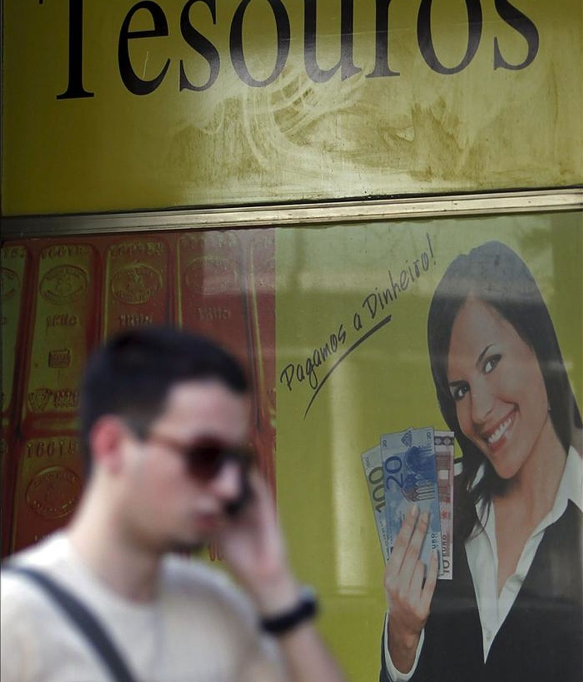 Un hombre habla por teléfono mientras pasa delante de una tienda en la que se compra oro en Lisboa, Portugal. EFE/Archivo