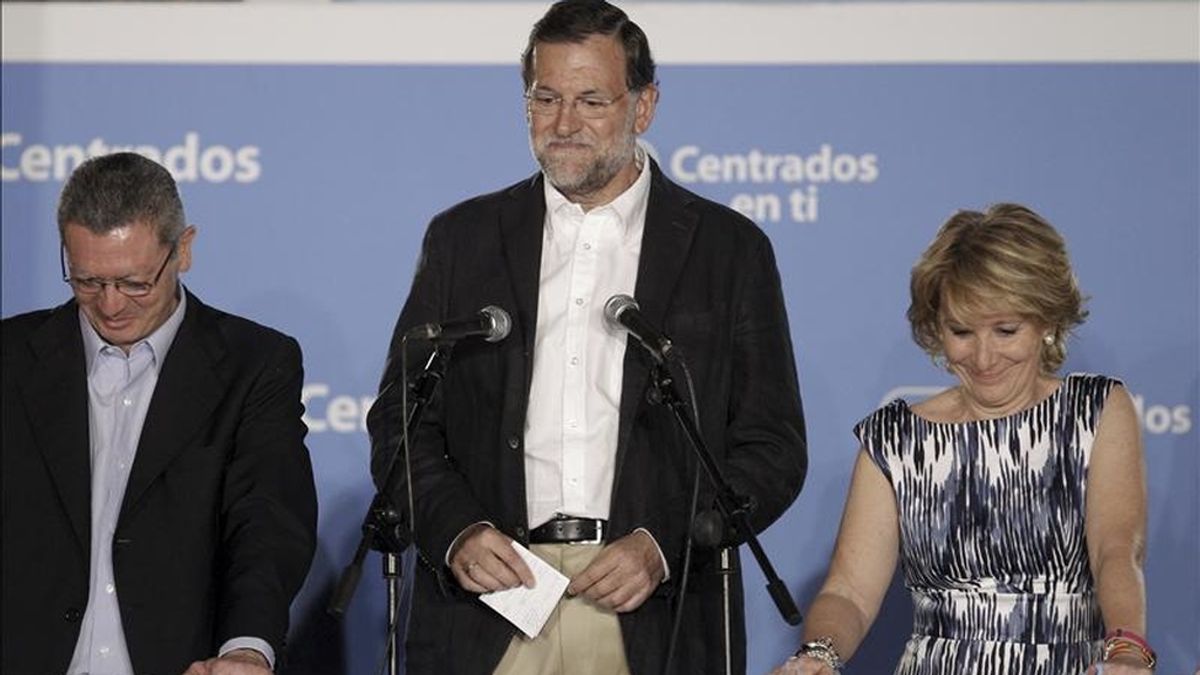 El presidente del PP, Mariano Rajoy (c), da un bote, junto al alcalde de Madrid, Alberto Ruiz Gallardón (i), y la presidenta de la Comunidad de Madrid, Esperanza Aguirre, celebran la victoria, esta noche en la sede del PP en Madrid, tras conocer los resultados electorales. EFE