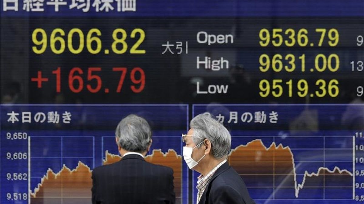 Dos ejecutivos japoneses caminan frente a una pantalla que muestra los valores de la Bolsa de Tokio (Japón). EFE/Archivo