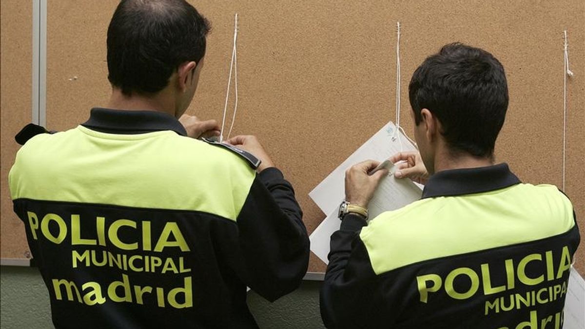 Un agente de la Policía Municpal de Madrid cuelga los listados con el censo electoral en un colegio público. EFE/Archivo