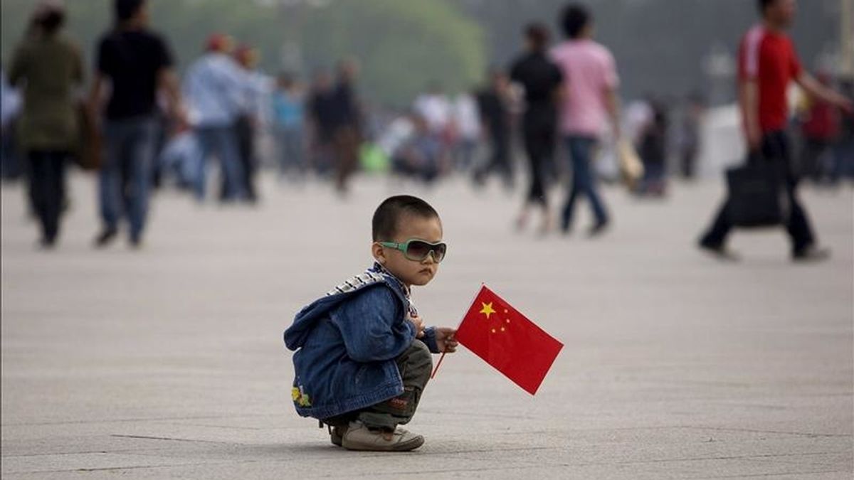 Un niño juega con una bandera china en la plaza de Tiananmen. EFE/Archivo