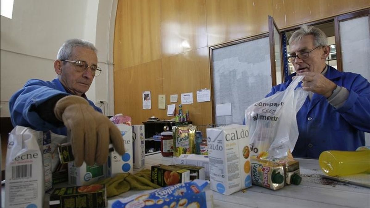 En la imagen dos voluntarios introducen alimentos de un banco de alimetación en bolsas para su posterior distribución. EFE/Archivo