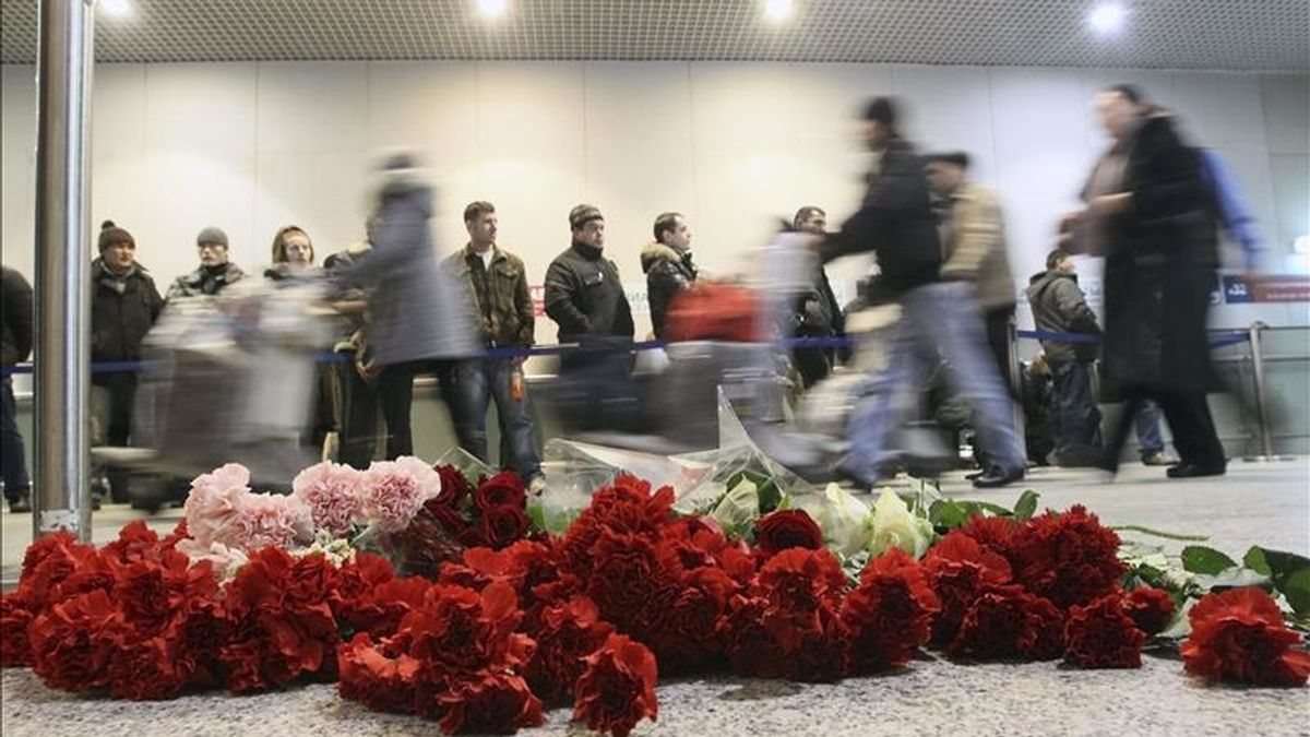 Los pasajeros caminan junto a varias flores que han sido depositadas en recuerdo a las 35 víctimas mortales del atentado perpetrado ayer en una zona común de acceso libre en la terminal de llegadas internacionales del aeropuerto moscovita de Domodédovo, en Moscú, Rusia, hoy, martes 25 de enero de 2011. EFE