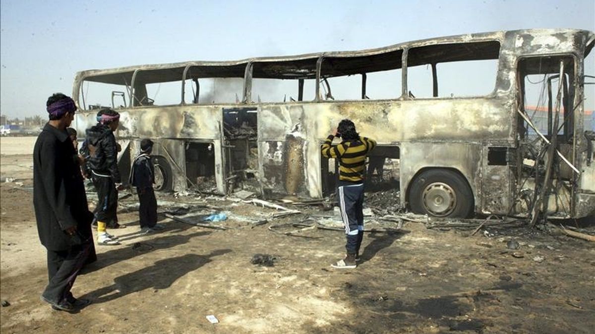 Unos jóvenes y unos niños observan un autocar carbonizado por efecto de un atentado en Kerbala, en el sur de Irak. EFE