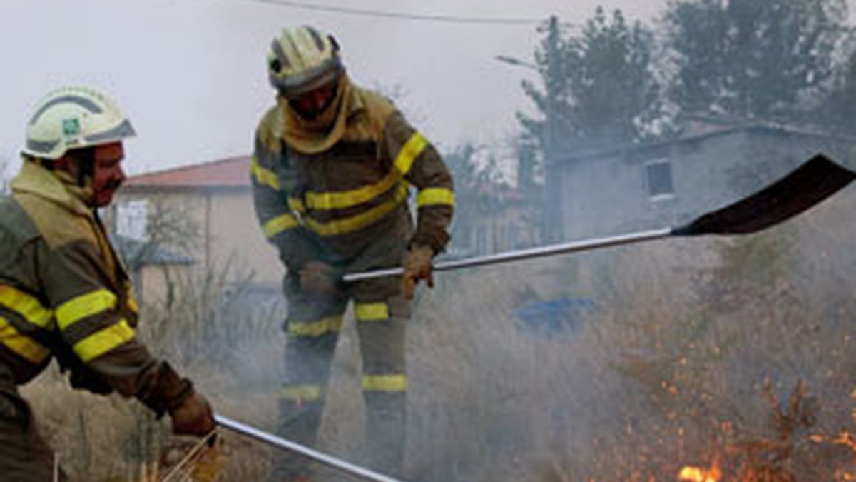 Varios brigadistas trabajaban para extinguir un fuego próximo a las casas, en el incendio declarado en Chás, en Montederramo (Ourense). Foto: EFE