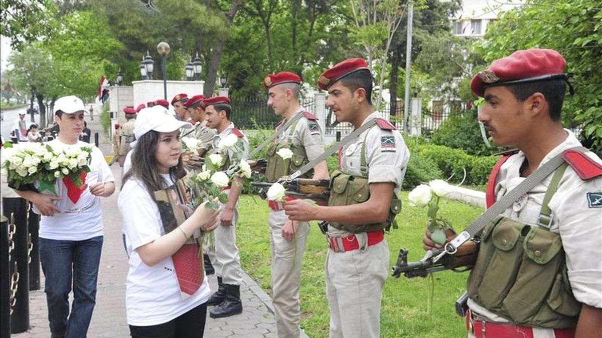 Imagen facilitada por la agencia siria de noticias Sana que muestra a jóvenes sirias ofreciendo flores a soldados sirios, en Damasco, Siria. EFE