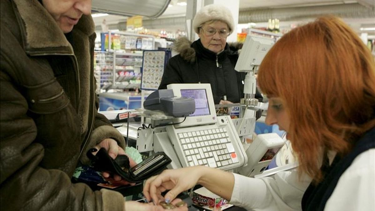 Una cajera ayuda a un cliente a contar monedas de euro en un supermercado. EFE/Archivo