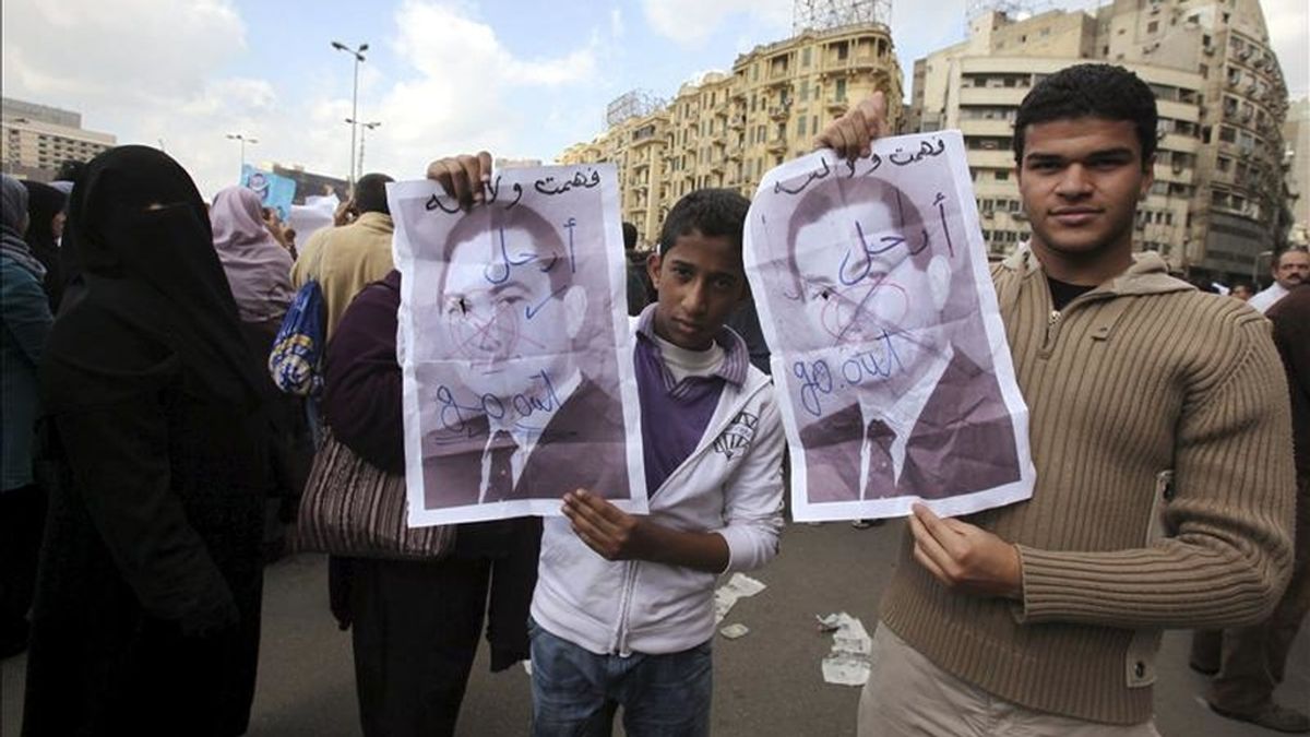 Dos hermanos despliegan una foto del presidente egipcio Hosni Mubarak durante una gran concentración en la plaza Tahrir, el corazón de El Cairo, para exigir la renuncia del actual régimen, en el séptimo día de manifestaciones contra el mandatario. EFE