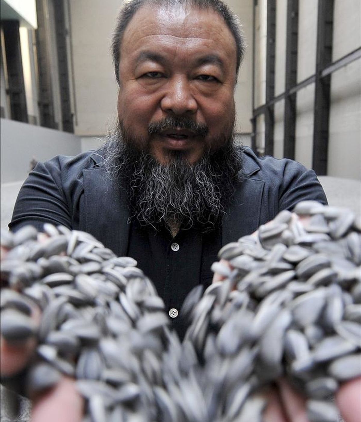 El renombrado artista chino Ai Weiwei sostiene un puñado de semillas de girasol de porcelana, durante la inauguración de su exhibición "Sunflower Seeds" en el Museo Tate Modern de Londres (Reino Unido), el 11 de octubre de 2010. EFE/Archivo