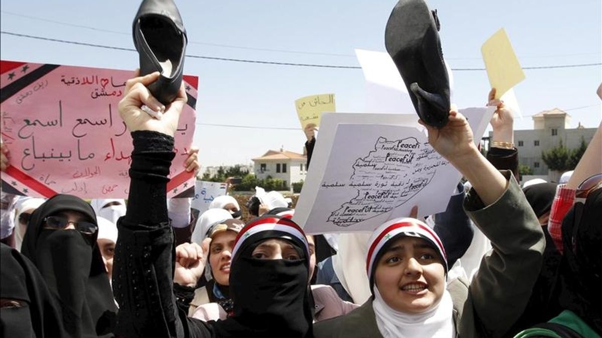Manifestantes sirios residentes en Jordania sostienen sus zapatos y gritan consignas en contra del presidente de Siria, Bashar al-Assad, durante una manifestación frente a la embajada siria en Ammán, Jordania, el domingo, 24 de abril. EFE